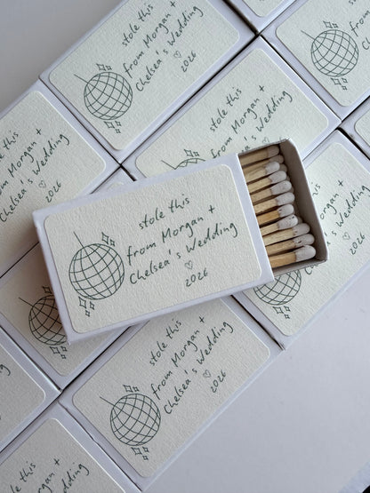 Stack of personalized disco ball wedding matchboxes with couple names, styled as wedding favors