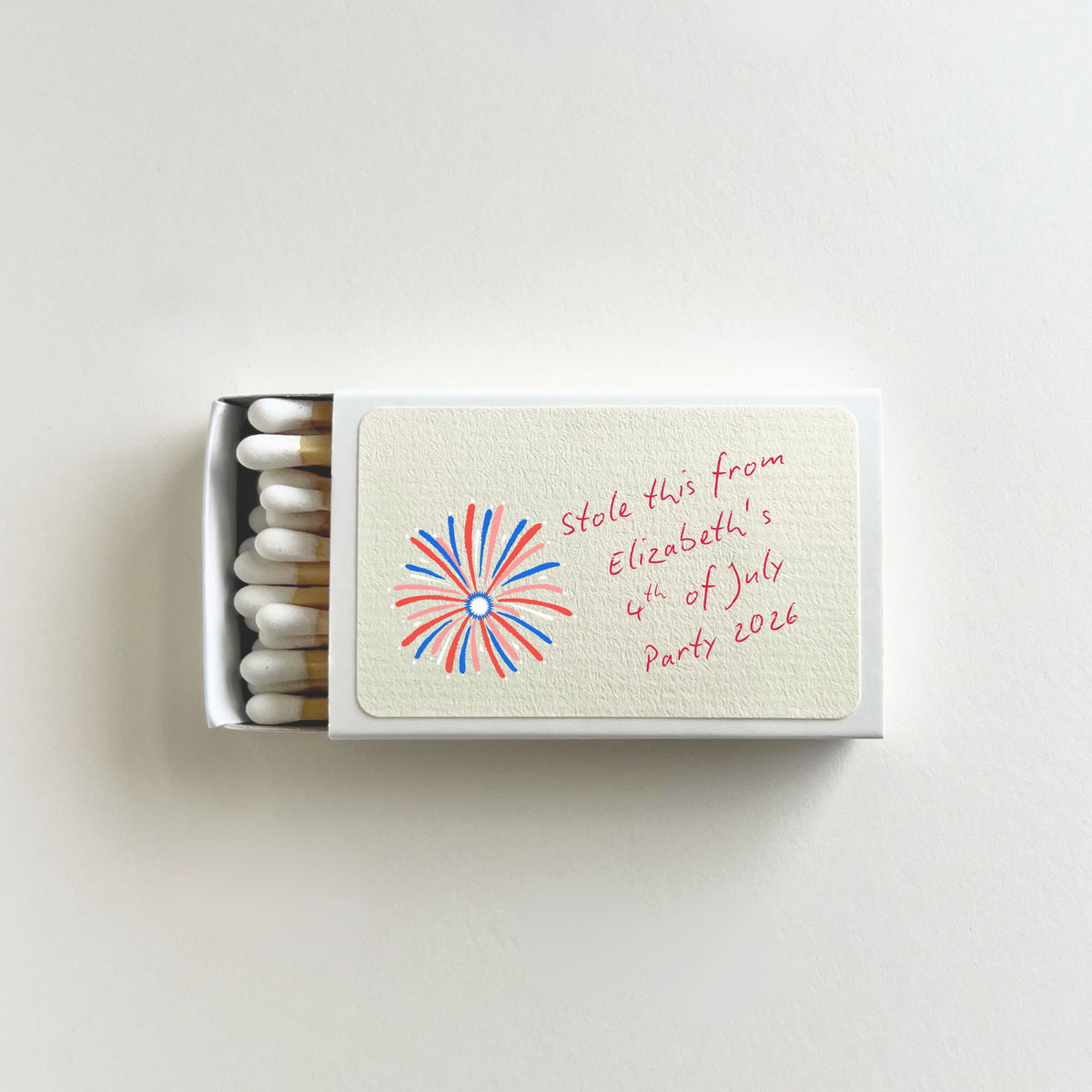Personalized 4th of July matchbook open to show white-tip matches, red white and blue fireworks illustration, and custom name on label